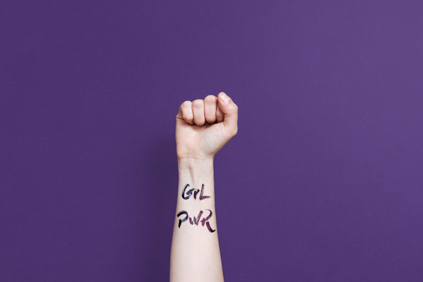 Clenched fist with girl power phrase on purple background